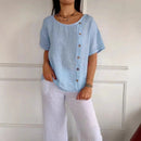 Blusa Amora™ em algodão leve com botões laterais, caimento solto e estilo casual, em tom natural.